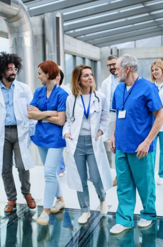 Front view of group of doctors walking in corridor on conference. Front view of group of doctors walking in corridor on conference, talking.